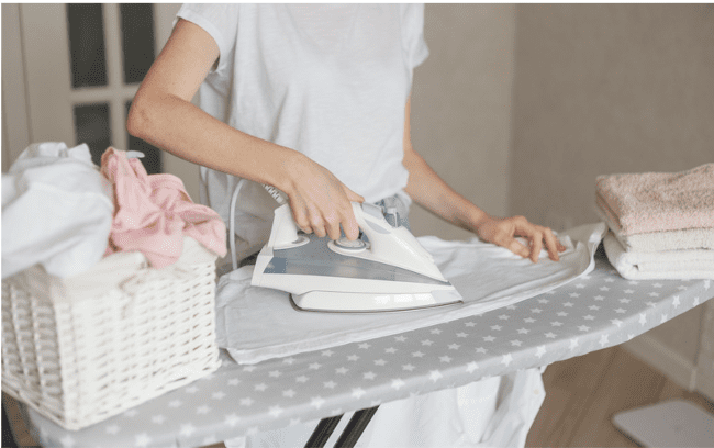 Femme repassant du linge sur une table de repassage.