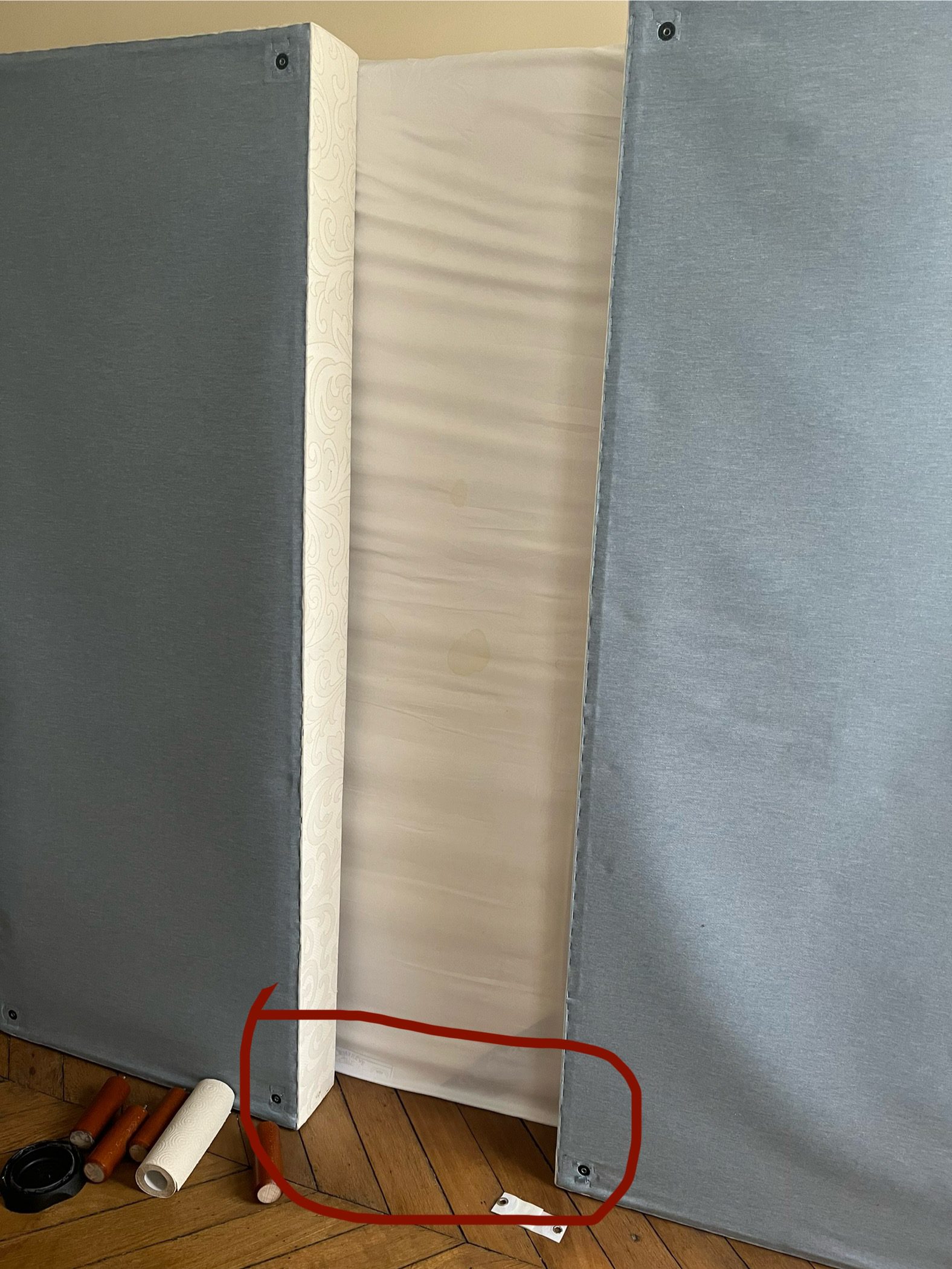 Inspection des zones basses d'un matelas avec une housse protectrice et des outils à proximité pour repérer les punaises de lit.