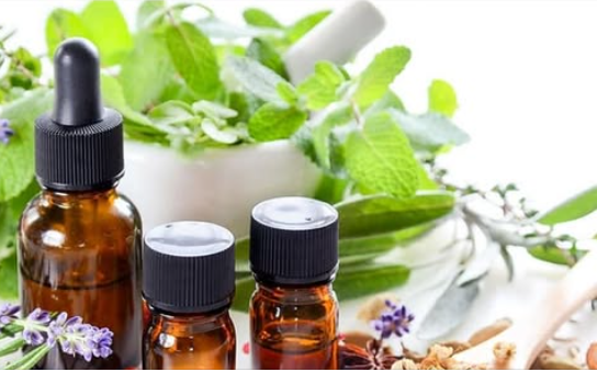 Bouteilles d'huiles essentielles entourées de plantes aromatiques, utilisées pour des traitements naturels.