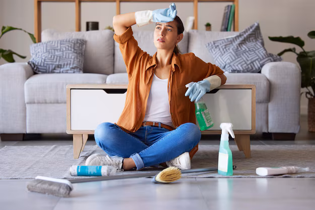Femme fatiguée nettoyant le sol avec des produits chimiques, illustrant une erreur courante dans le traitement des punaises de lit.