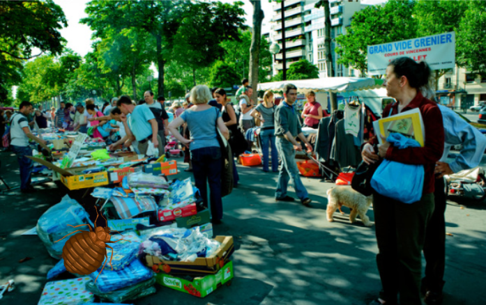 Vide-grenier en plein air avec vêtements d’occasion, objets de seconde main et foule de chineurs.