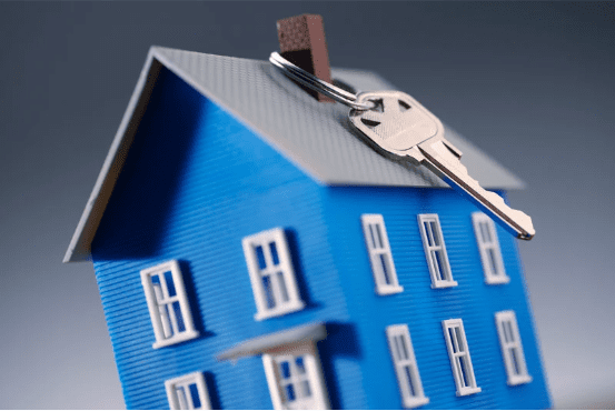Maquette de maison bleue avec une clé sur le toit, symbolisant la location ou la copropriété