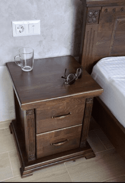 Table de chevet en bois à côté d’un lit, zone à inspecter en cas de punaises de lit